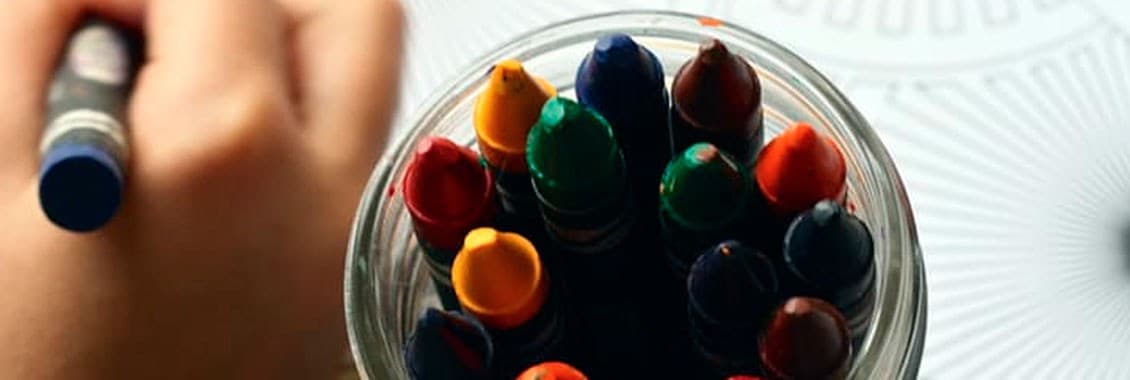 Crayones y la mano de un niño explorando con libertad